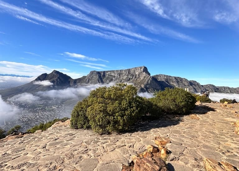 Table Mountain beyond a rocky foreground and low cloud in Cape Town.