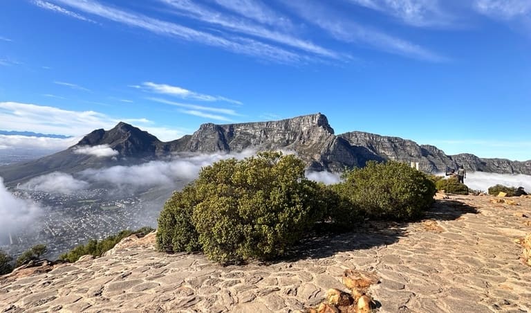 Table Mountain beyond a rocky foreground and low cloud in Cape Town.